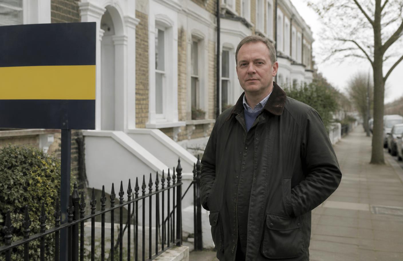 A landlord standing outside a Victorian terraced rental property on a UK street